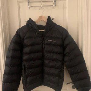 Svart dunjacka från Peak Performance - Säljer en svart dunjacka från Peak Performance i mycket bra skick. Jackan är perfekt för vintern med sin pufferstil och långa ärmar. Den har en praktisk dragkedja och är supervarm och skön. Perfekt för kalla dagar!