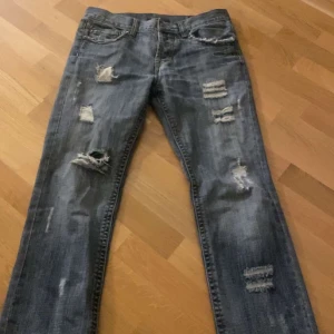 Blå jeans med slitningar - Säljer ett par blå jeans i bra skick med coola slitningar på framsidan.  De är flared/ lite baggy beror på hur de sitter på en❤️ skriv privat om mått eller om du undrar något annat om byxorna 