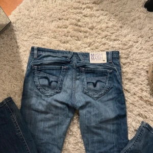 Blå jeans från Mish Mash - Säljer ett par snygga blå jeans från Mish Mash. Säljer då de är väldigt stora på mig vid midjan. Passar någon som bär på kanske M/L. Annars passar längden perfekt på mig, är 1.62, passar någon som är 1.70. Ett par små vita fläckar där nere men inget man lägger märke till. Inga hål