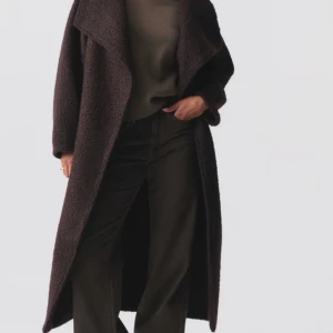 Mörkbrun kappa med bälte - Säljer en superfin mörkbrun kappa med bälte i midjan. Den har en lång och elegant design med breda slag och långa ärmar. Perfekt för höst och vinter när du vill hålla dig varm. Ny med prislappen på. 