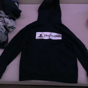 Svart PlayStation hoodie - Säljer en svart PlayStation hoodie i bra skick. Den har en stor logga på framsidan och är perfekt för gamingkvällar eller chill. Hoodien har långa ärmar och en klassisk passform. Perfekt för höst och vinter!