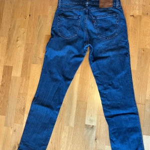 Blå jeans från Levi's - Säljer ett par klassiska blå jeans från Levi's i bra skick. De har en straight passform och är perfekta för vardagsbruk. Skön passform och väldigt slittåliga. Inga defekter. Storlek W34 L32. Snabb affär= lägre pris