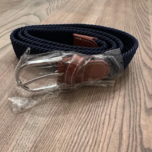 Blått flätat bälte med bruna detaljer - Säljer ett snyggt blått flätat bälte! Bältet är i nytt skick och är aldrig använd. Passar bra till jeans.🥂