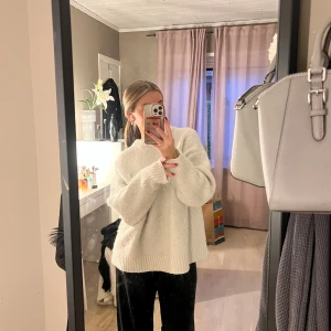 Vit stickad tröja - Mysig vit stickad tröja från Zara. Den har en avslappnad passform med långa ärmar och ribbade kanter vid ärmslut och nederkant. Den är lite nopprig men annars fint skick!