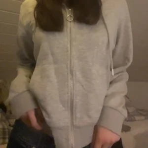 Grå zip-up - Säljer en grå zip-up i storlek XL med den är ganska liten i storlek o skulle säga att den sitter som en M. Den är skön och perfekt för mysiga dagar. Hoodien har dragkedja och en praktisk huva med snören. Den är i bra skick och passar perfekt till vardagsoutfiten.