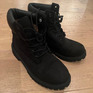 Svarta  Timberland 38 ny  - Säljer ett par svarta kängor från Timberland . De har en robust sula och snörning framtill, perfekt för höst och vinter. Kängorna är gjorda i skinn och har en bekväm passform. Perfekta för att hålla fötterna varma och torra under kalla dagar.