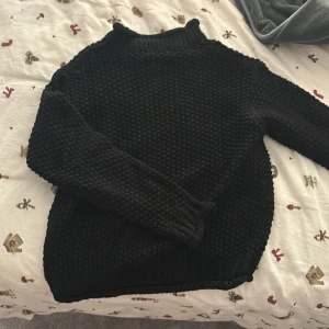 Svart stickad tröja från NA-KD - Mysig svart stickad tröja från NA-KD i storlek S. Perfekt för kyliga dagar med sin tjocka stickning och långa ärmar. Tröjan har en klassisk design med ribbstickad krage och muddar. Passar både till vardags och mysiga hemmakvällar. 🖤