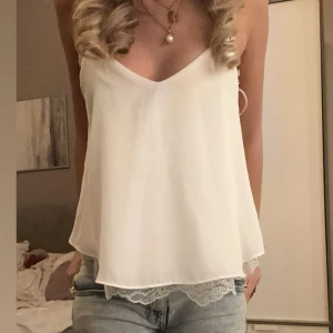 Vit ärmlös topp med spetsdetaljer - så fint linne med spets! i super bra skick som inte säljs längre 