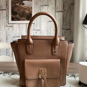 Brun handväska från Giuliano - Snygg brun handväska i skinn från Giuliano. Den har en praktisk framficka med spänne och dragkedja baktill. Perfekt för både vardag och fest! 👜