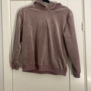 Gammelrosa hoodie i sammet i strl 14 (164) från Designers remix - Gammelrosa hoodie i sammet i strl 14 (164) från Designers remix.  Använd men i fint begagnat skick.  Mått Över bröstet: ca 51 cm Längd från axeln och ner: ca 57 cm  Polyester, spandex och bomull   Kommer från ett djur och rökfritt hem.