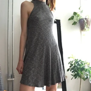 Hollister ribbstickad klänning - Gråmelerad, ribbstickad klänning från Hollister märkt M (det är en liten M och känns mer som en S). 65% viskos 35% polyester. Halvpolo som knäpps med två knappar baktill, assymetrisk nedtill. Använd ett fåtal gånger - i gott skick 🤍 1:a bilden lånad.