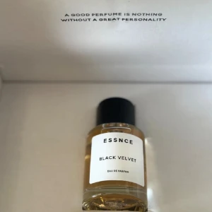 Essnce Black Velvet Eau de Parfum - Säljer en ny flaska Essnce Black Velvet Eau de Parfum. Den har en elegant och stilren design med en svart kork och en genomskinlig flaska som visar den gyllene parfymen inuti. Perfekt för den som vill ha en sofistikerad doft med en touch av mystik.