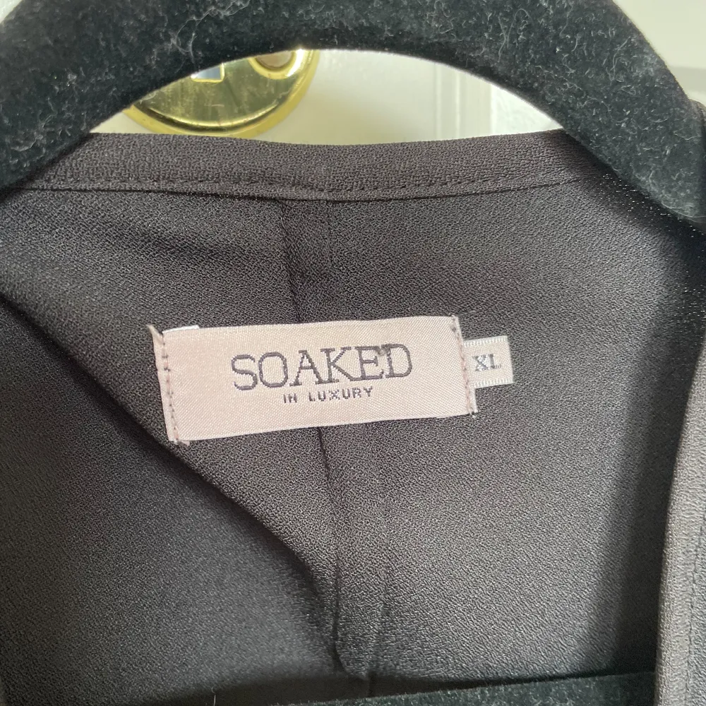 Säljer en elegant svart kavaj från Soaked in Luxury. Den har vida ärmar och en stilren design som passar perfekt för både vardag och fest. Materialet känns mjukt och bekvämt. Perfekt för att ge din outfit en chic touch!. Takit.