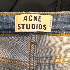 Blå jeans från Acne Studios - Säljer ett par snygga blå jeans från Acne Studios. De är i en klassisk denimfärg och har en straight passform. Perfekta för både vardag och fest! De är i storlek 27/34 och har en bekväm midwaist. Jeansen är i bra skick och redo för en ny ägare.