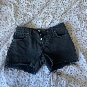 Svarta 90-tals boyfriend shorts - Säljer ett par svarta 90-tals inspirerade boyfriend shorts i denim. De är lågmidjade och har en avslappnad passform med fransiga kanter. Perfekta för en cool och avslappnad stil!