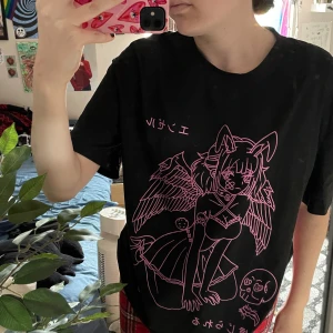 Svart t-shirt med rosa anime-tryck - Säljer en svart t-shirt med ett coolt rosa anime-tryck på framsidan. T-shirten har korta ärmar och en normal passform. Perfekt för dig som gillar unik och  stilren design! Köpt typ 2020