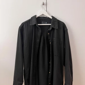 Jeansskjorta - Säljer en lite oversize svart jeansskjorta storlek 38/40 från Asos. Väldigt lite använda☺️