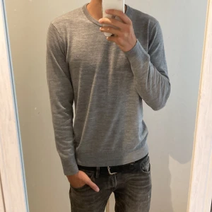 Grå tröja i merinoull från Uniqlo - Säljer en sprillans ny, stilren och bekväm grå tröja från Uniqlo i extra fin merinoull. Perfekt för både vardag och lite finare tillfällen. Tröjan är maskintvättbar och har en normal passform med långa ärmar. Supermjuk och håller dig varm under kyliga dagar! Storlek M men passar även S.