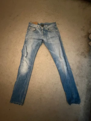 Ljusblå slim fit jeans - Säljer min killes gamla as snygga ljusblå jeans med slim fit passform och klassisk femficksdesign. Jeansen har slitningar och tvättade detaljer för en cool, avslappnad look. Perfekta till sneakers och hoodie för en trendig stil.