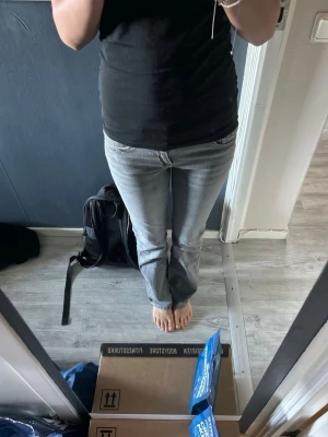 Grå bootcut jeans med broderade fickor - Snygga grå bootcut jeans med slitningseffekt och broderade bakfickor. Jeansen har klassisk femficksdesign, knappgylf och raka ben med lätt utsvängning. Perfekta för en trendig och avslappnad look.