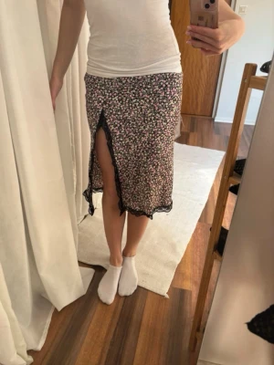 Kjol med spets slits - Blommig kjol med svart spets slits på sidan. Finns inte längre att köpa och knappt använd. 