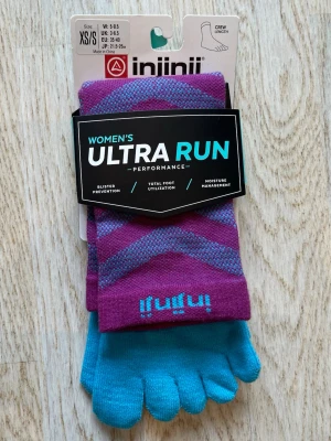 Lila och turkosa tåstrumpor Injinji - Säljer ett par tåstrumpor från Injinji i lila och turkos med randigt mönster. Strumporna är tillverkade i en mix av Coolmax, nylon och lycra, perfekta för löpning och träning. Crew-längd och designade för att motverka blåsor och hantera fukt. Fått som present, aldrig använt. Orginalpris: runt 200. Tveka inte på att skriva en fråga eller be om fler bilder.🌸🌸