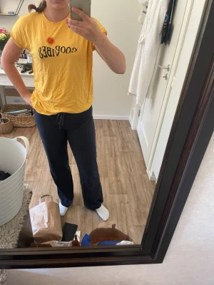 Gul t-shirt med tryck från ADPT - Gul t-shirt från ADPT med svart text 'GOOD VIBES' och en röd sol på bröstet. Klassisk passform med korta ärmar och rund halsringning. Tillverkad i mjuk bomull, perfekt för en avslappnad och cool stil.