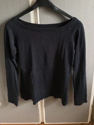 Svart långärmad tröja med bred hals - Svart långärmad tröja  Mjukt, tunt och stretchigt material som sitter snyggt på kroppen. Bred ribbad halsringning och ribbade muddar. 
