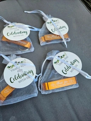 Guldfärgade nyckelringar med tacketikett - Fyra guldfärgade nyckelringar i metall med texten 'Thank You for celebrating with us' och hjärtmotiv. Varje nyckelring ligger i en vit organzapåse med rund etikett och dekorativt band. Perfekt som gåva vid fest eller bröllop. 4 stycken för 160 kr