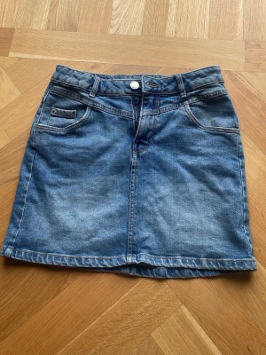 Blå jeanskjol med fickor - Snygg blå jeanskjol i klassisk modell. Den här storlek 152 men den passar på nästan alla (det bror på vilken längd man vill ha)
