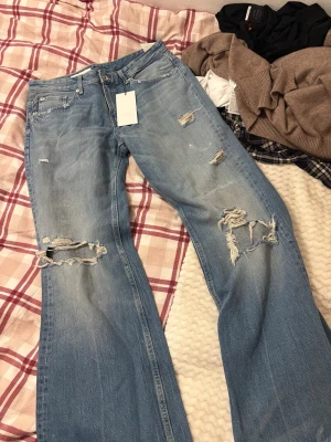 Ljusblå slitna jeans med raka ben - Säljer ett par ljusblå jeans från Zara med raka ben och flera slitningar och hål på både fram- och baksida. Jeansen har klassisk femficksmodell och är tillverkade i denim. Lapparna kvar. Aldrig använda 