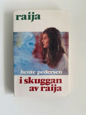 I skuggan av Raija av Bente Pedersen - Raija 14 - Boken "I skuggan av Raija" av Bente Pedersen. Fristående del i den storslagna Raija - serien, en släkt- och kärlekssaga fylld av mystik och trolldom, där livet vid nordkalotten prövas av öde, passion och kamp för frihet. En episk berättelse om kärlek, hämnd och övernaturliga krafter.   ISBN: 91-7710-456-0.
