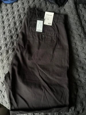 Svarta shorts Style: LEO - Säljer ett par svarta shorts i modellen LEO, storlek L. Klassisk design med bakficka och knapp, bälteshällor och rak passform. Lappen är kvar 
