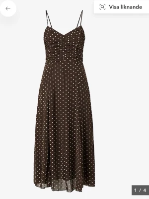 Mango klänning  - Säljer en brun långklänning med vita prickar och tunna axelband. Klänningen har en smickrande rynkad överdel och ett luftigt, svepande fall. Perfekt för dig som gillar en feminin och trendig look.