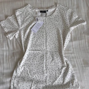 Vit prickig t-shirt från KappAhl - Tillverkad i mjuk bomull och perfekt till jeans eller kjol.