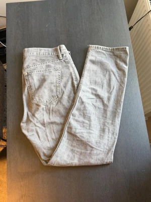 Grå relaxed fit jeans från H&M - Säljer ett par gråa relaxed fit jeans från H&M. Jeansen har klassisk femficksdesign, raka ben och är tillverkade i ett mjukt denimtyg. Perfekta för en chill och avslappnad stil.