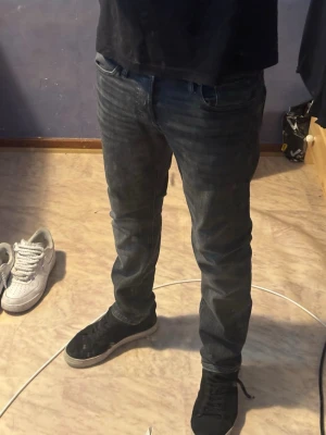 Mörkgrå  jeans herr - Säljer ett par mörkblå slim fit jeans med klassisk femficksdesign och lätt tvättad look. Jeansen har normal midja och smal passform hela vägen ner. Perfekta för dig som gillar en enkel och stilren stil.