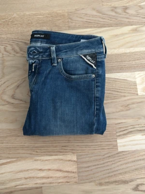 Blå jeans från Replay - Snygga blå jeans från Replay med klassisk femficksmodell och detaljerade sömmar. Jeansen har en läderpatch med Replay-logga bak i midjan och diskreta slitningar för en cool look. Tillverkade i slitstarkt denimtyg.