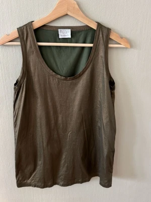 Olivgrön linnetopp från Brunello Cucinelli - Snygg olivgrön linnetopp från Brunello Cucinelli med rund halsringning och ärmlös design. Tillverkad i ett mjukt och svalt material som passar perfekt till varma dagar. Enkel och stilren modell som är lätt att matcha med olika outfits.0786