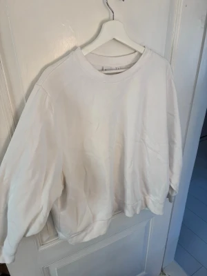 Vit oversized hoodie från Kappahl - Säljer en enkel och stilren vit hoodie från Kappahl i storlek L. Hoodien har en loose passform, ribbade muddar vid ärmslut och nederkant samt rund halsringning. Perfekt för en avslappnad och clean look.