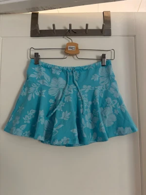 Kort kjol - Söt kortkjol med ljusblått/turkost blommigt mönster som är perfekt under sommaren! Kjolen har shorts under, se sista bilden. Från Bershka i storlek XS, men skulle saga att den även passar S. Aldrig använd med lappen kvar, säljer då den tyvärr inte passar mig💕