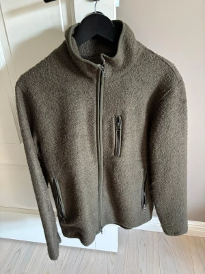 Olivgrön fleecejacka John Henric - Säljer en olivgrön fleecejacka från John Henric med hel dragkedja framtill, hög krage och tre fickor med dragkedja. Materialet är mjukt och värmande, perfekt för kyliga dagar. Enkel och stilren design som passar till det mesta.