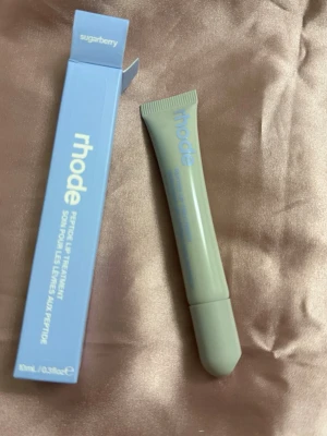 Rhode Peptide Lip Treatment Sugarberry - Rhode Peptide Lip Treatment i doften Sugarberry. Kommer i en stilren, ljusgrå tub med blå text och matchande blå förpackning. Innehåller 10 ml och är perfekt för att återfukta och vårda läpparna med en fräsch bärdoft.