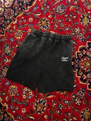 Svarta shorts från Brand of Roses - Säljer ett par svarta shorts från Brand of Roses med elastisk midja och diskret logga broderad framtill. Shortsen har en loose passform och är perfekta för chill dagar. Materialet känns mjukt och bekvämt, troligen bomull eller en bomullsblandning. KLIPPTA TILL SHORTS SJÄLV!