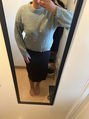 Grön stickad tröja med pärlor - Mysig grön stickad tröja med rund halsringning och dekorativaVit kort klänning med spetsrygg pärlor över hela tröjan. Modellen är något kortare och har långa ärmar samt ribbstickade muddar vid ärmslut och nederkant. Perfekt för en trendig och stilren look.