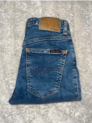 Nudie jeans  - Ett par snygga blåa skinny jeans från Nuie Jeans. Midja 28cm, längd 93cm. Obs jeansens benslut är avklippta, så kolla måtten. För storleksguide kolla måtten noggrant då jeansen alltid kan vara uppsydda heller krympta och jag ej tar emot returer :) (n11)
