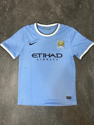 Manchester City 2013 Matchtröja - Som ny Manchester City fotbollströja  Tröjan är endast använd en gång och är i mycket fint skick, som ny. Inga skador eller fläckar.  Pris: 225kr – tycker det är ett bra och rimligt pris för tröjan. Priset kan diskuteras vid snabb affär.  Skickas snabbt och packas ordentligt.