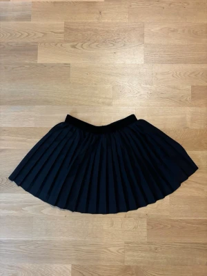 Svart plisserad kortkjol från H&M - Säljer en svart plisserad kortkjol från H&M i storlek 38. 