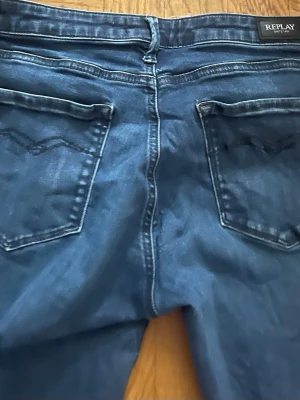Mörkblå jeans från Replay - Snygga mörkblå jeans från Replay med klassisk femficksdesign och raka ben. Jeansen har dekorativa sömmar på bakfickorna och är tillverkade i ett mjukt denimtyg som ger en skön passform. Perfekta för dig som gillar stilrena och tidlösa jeans. Midja 28 längd 32