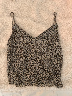 Leopardmönstrad linnetopp från Bershka - Säljer en snygg leopardmönstrad linnetopp från Bershka i beige och svart. Toppen har tunna axelband och är perfekt för dig som vill sticka ut lite extra. Materialet känns lätt och luftigt, perfekt för varma dagar. Banden är inte justerbara